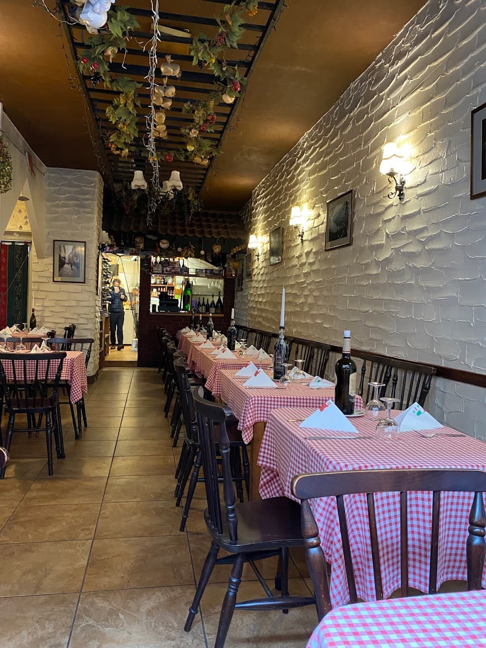 Etna's dining room: red gingham tablecloths, whitewashed stone walls and warm lamplight